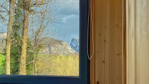 Un dormitorio con cabecera de madera, una ventana con vistas a árboles y una montaña.