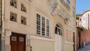 Un bâtiment à deux étages, doté d’une façade beige, d’un toit recouvert de tuiles rouges et d’une entrée au rez-de-chaussée avec une porte en bois.
