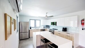 Una cocina moderna con armarios blancos, electrodomésticos de acero inoxidable y una isla central con taburetes de bar.