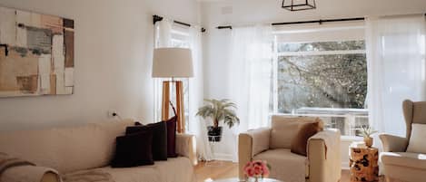 A modern living room with a beige sofa, a round coffee table, and a potted plant.