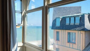 Une pièce dotée de grandes fenêtres donnant sur un bâtiment avec un toit en pente et un balcon.