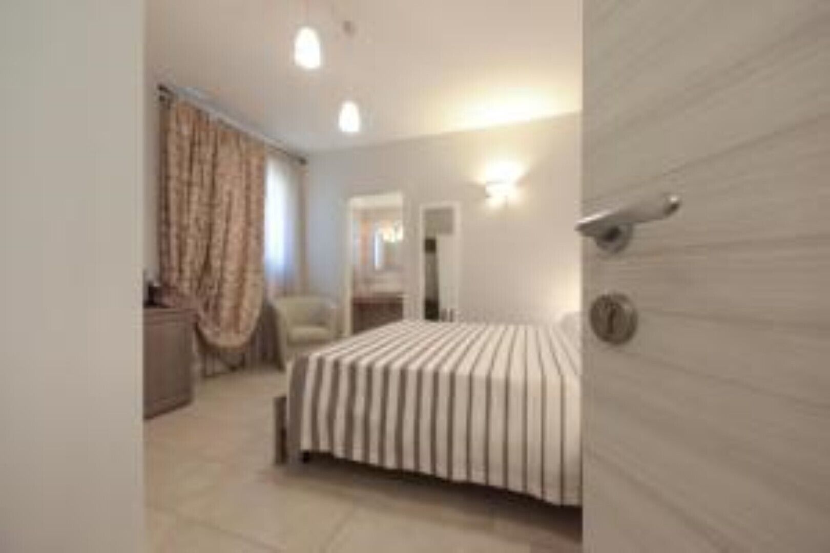 A hotel room with a bed, a chair, a desk, and a wardrobe.