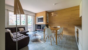 A modern living room with a sofa, dining table, and chairs. There is a fireplace, a TV mounted on the wall, and a large window providing natural light. - Ecluses 6 - Nendaz centre & close to ski lift (Haute-Nendaz)
