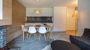 A modern kitchen with a dining area, featuring a wooden table, white chairs, and a hanging light fixture. - Ecluses 6 - Nendaz centre & close to ski lift (Haute-Nendaz)