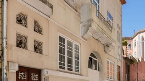 Um edifício de dois andares com fachada bege, telhado de telhas vermelhas e entrada térrea com porta de madeira.