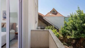 Uma varanda com vista para um edifício vizinho e vegetação.