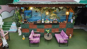 A cozy outdoor seating area with two purple chairs, a small round table, and a mural depicting a tropical scene. - PALVAN ACCOMMODATION (Antalya)