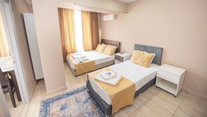 A hotel room with two beds, a small table, a nightstand, and a bathroom door. - PALVAN ACCOMMODATION (Antalya)