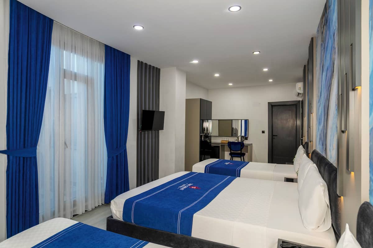 A hotel room with two beds, a desk, a chair, a TV, and a bathroom door.