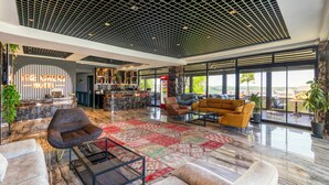 Eine geräumige Lobby mit modernem Design, ausgestattet mit einer großen Sitzgruppe, einer Rezeption und großen Fenstern mit Blick auf die Stadt.