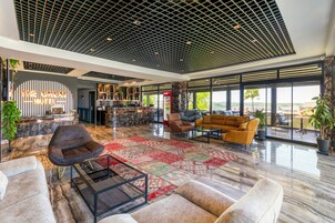 Un vestíbulo amplio con diseño moderno, que cuenta con una zona de estar amplia, un mostrador de recepción y ventanas grandes con vistas a la ciudad.