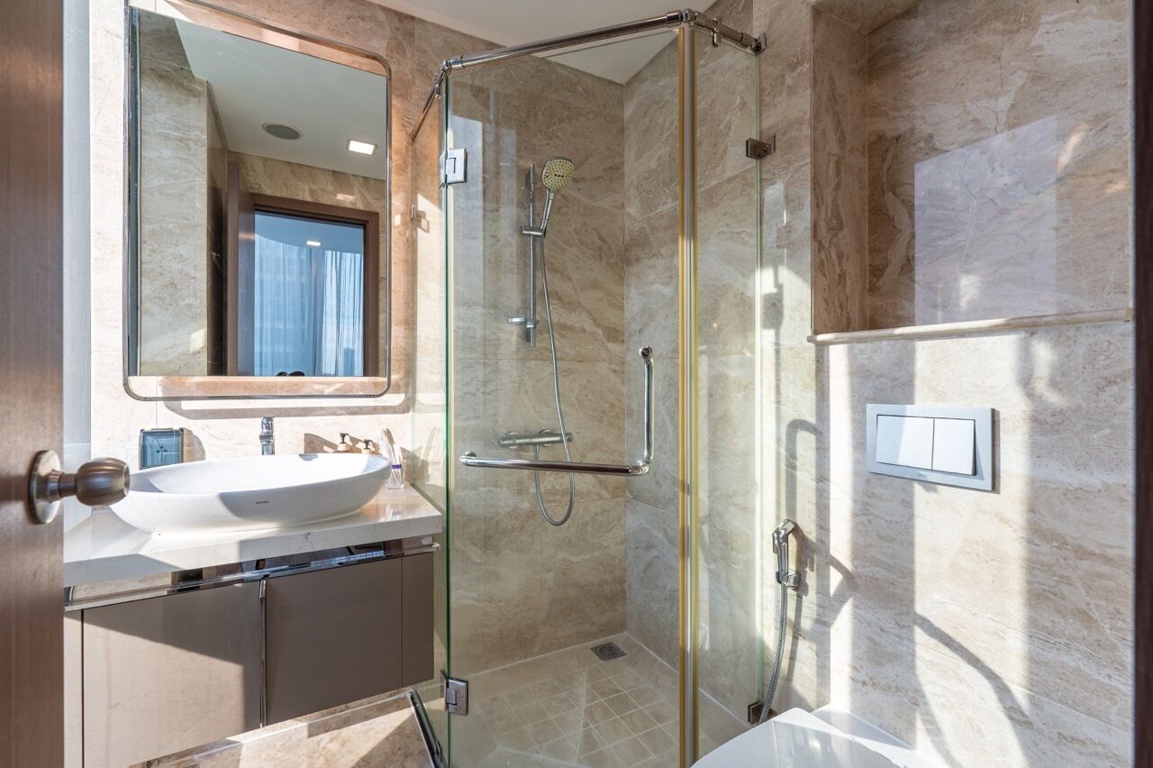 Un baño moderno con ducha envuelta en vidrio, un lavabo blanco y un espejo grande.