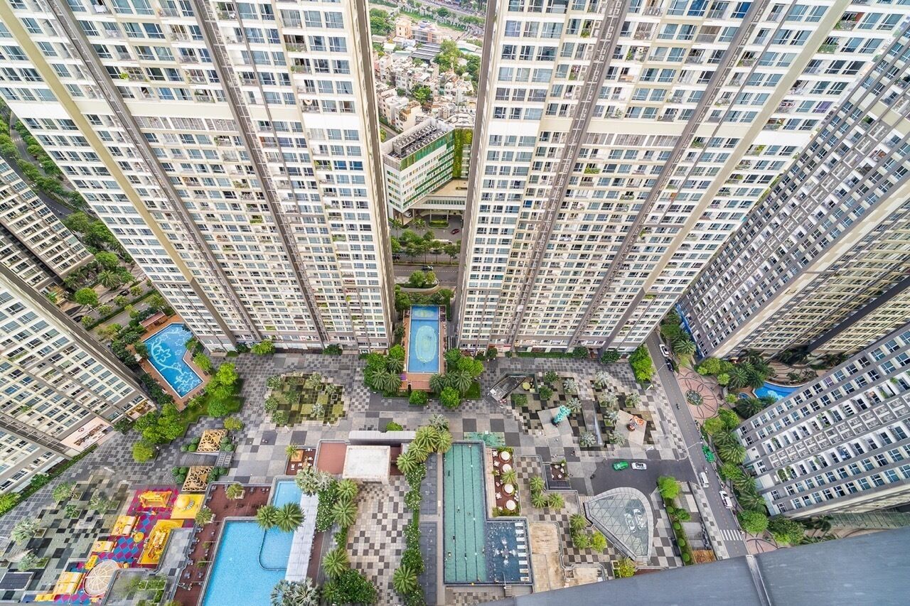 Un edificio residencial alto con varios balcones, un patio central con piscina y abundante vegetación.