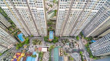 A high-rise residential building with multiple balconies, a central courtyard with a pool, and surrounding greenery.