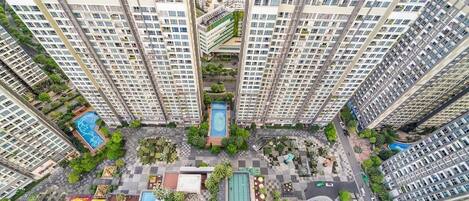 Un edificio residencial alto con varios balcones, un patio central con piscina y abundante vegetación.