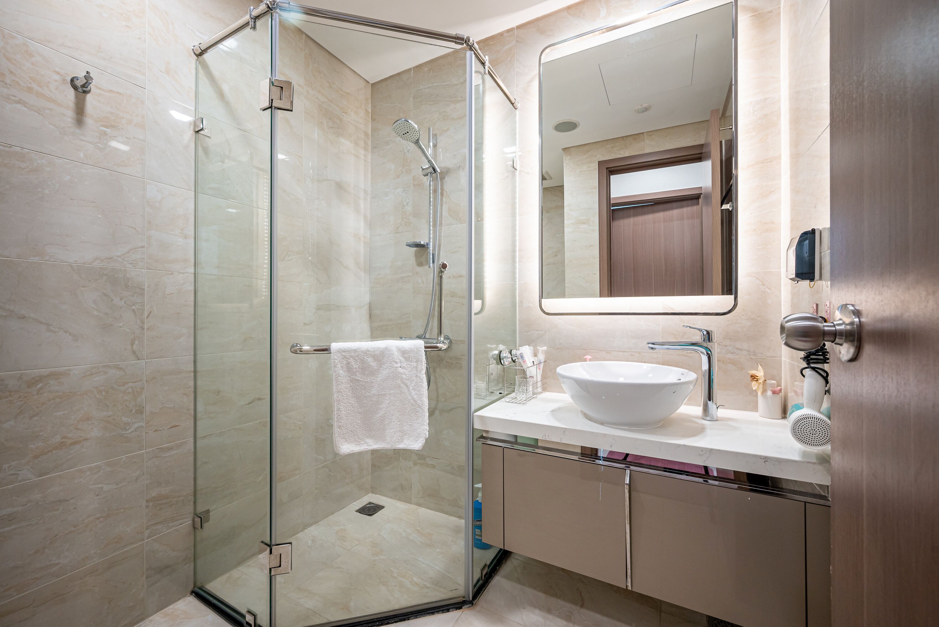 Un bagno moderno con doccia vetrata, lavandino bianco e uno specchio grande.