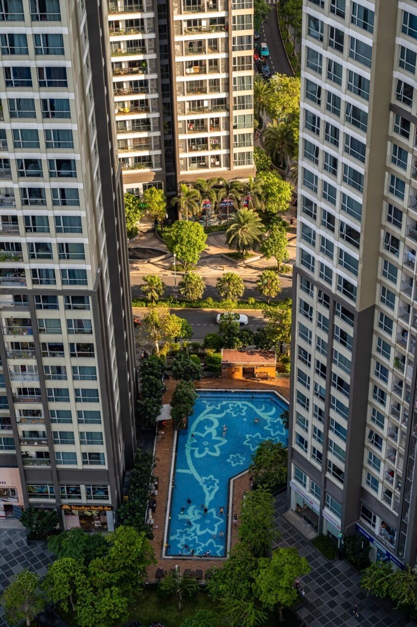 A high-rise building with a central courtyard featuring a swimming pool.