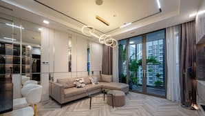 Una sala de estar moderna con un sofá seccional, una mesa de centro de vidrio y un ventanal con vistas a un paisaje urbano.