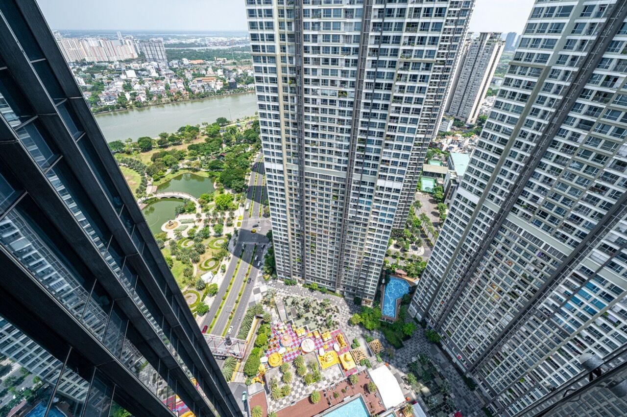 A high-rise building with a view of a river and park area below.