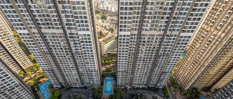 Un immeuble de grande hauteur, doté de nombreux étages, une cour intérieure avec une piscine et des espaces verts environnants.