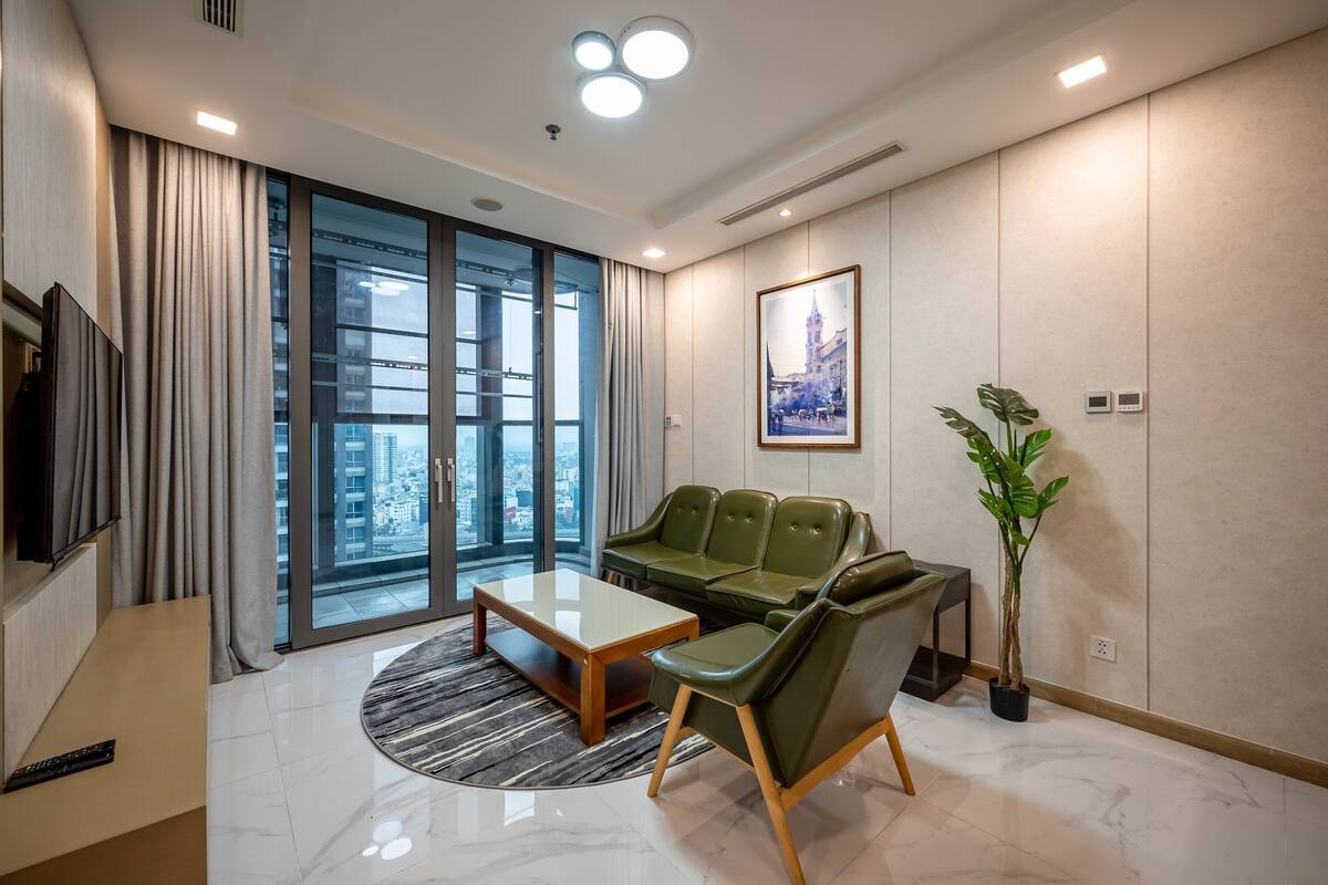 A modern living room with a sofa, coffee table, and a large window offering a city view.