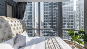 Un dormitorio con un ventanal grande, una cama y una planta en maceta.