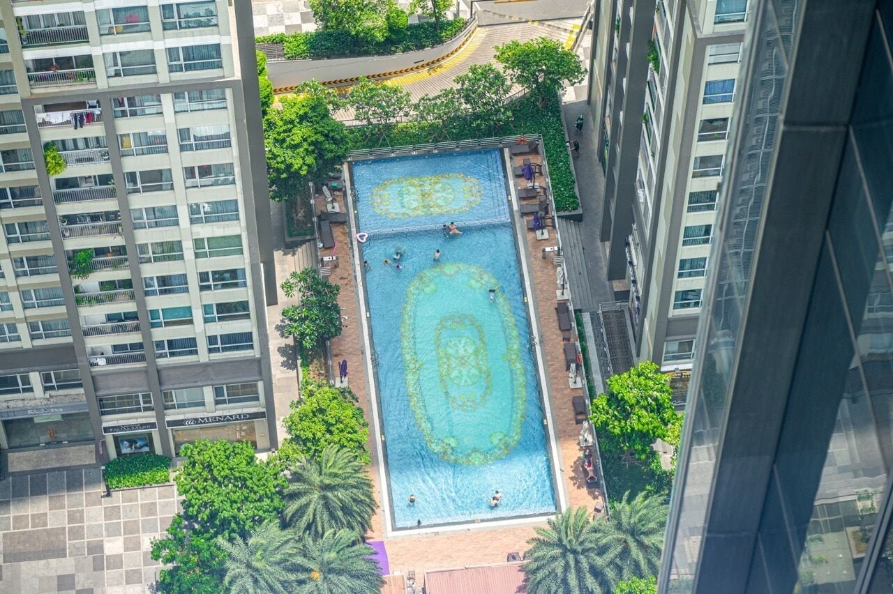 Una piscina en la azotea rodeada de edificios altos, con un cielo despejado.