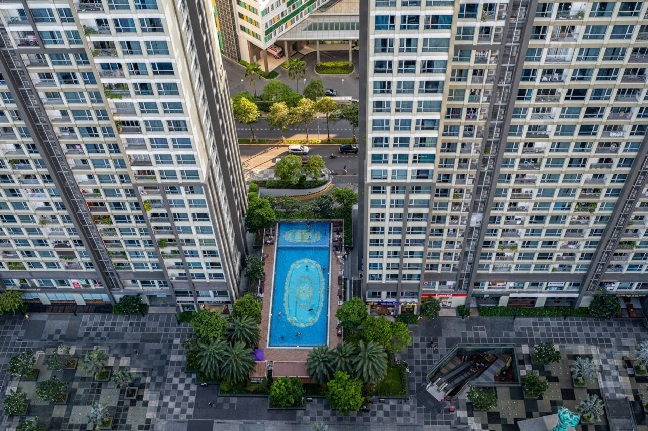 A high-rise building with a central courtyard featuring a swimming pool, surrounded by greenery and pedestrian pathways.