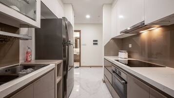 A modern kitchen with stainless steel appliances, a marble countertop, and a view into the adjacent bathroom.