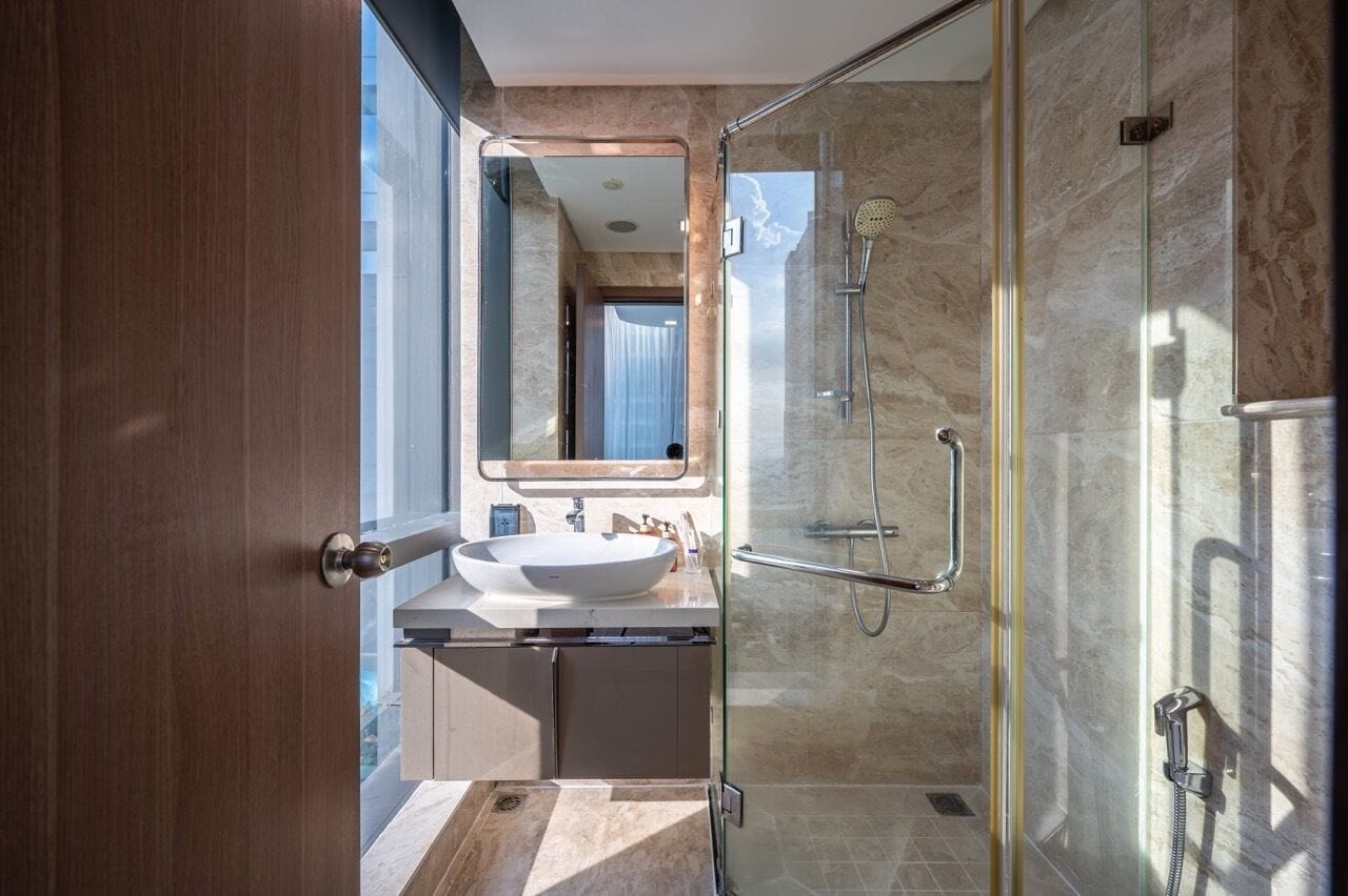 Un baño moderno con cabina de ducha de vidrio, un lavamanos blanco y un espejo grande.