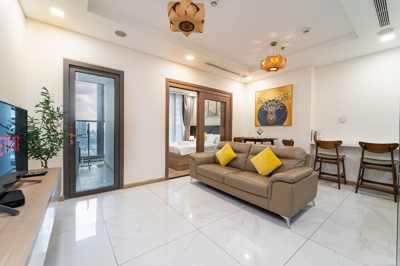 A modern living room with a sofa, chairs, a TV, and a balcony.