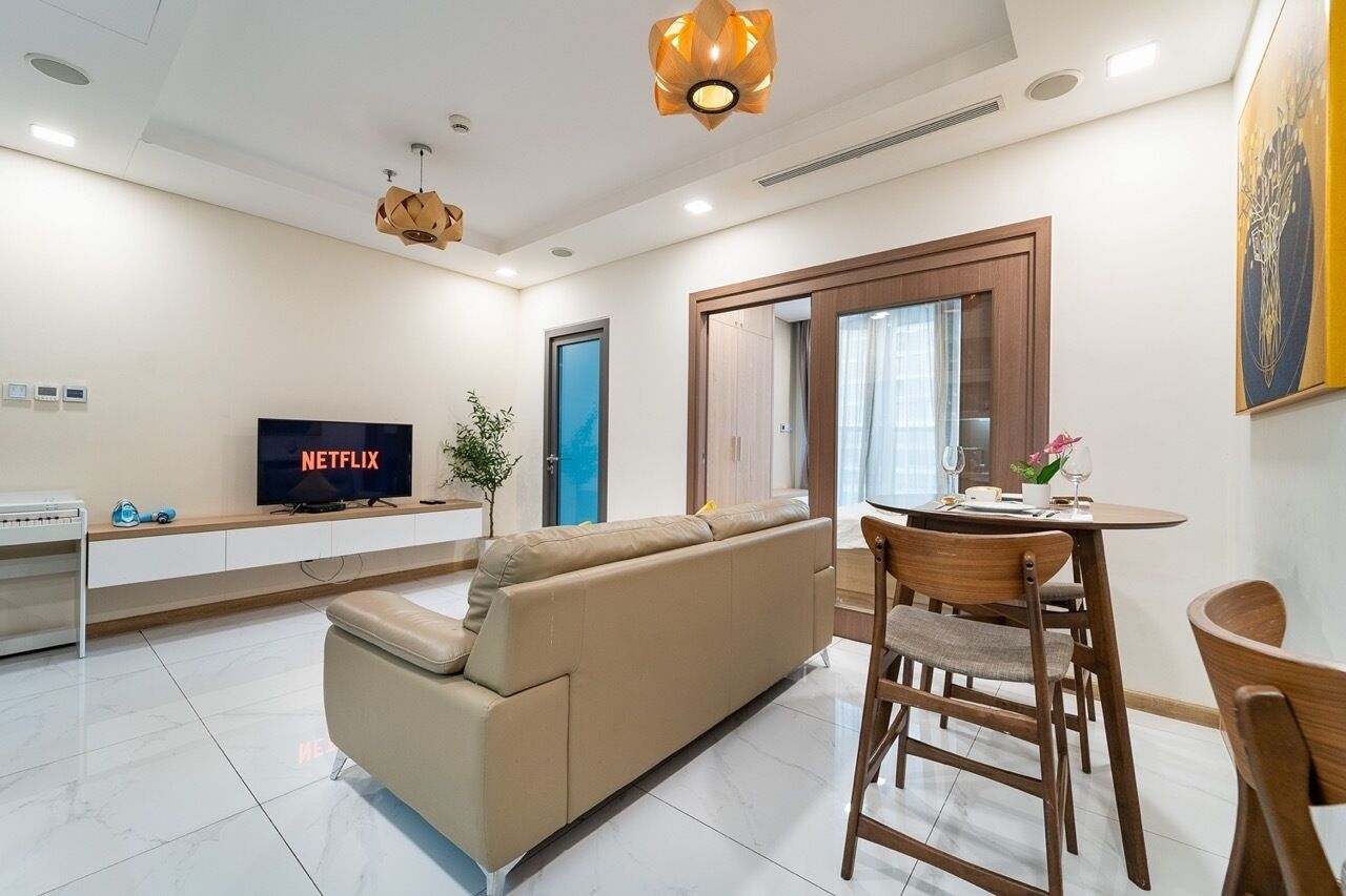 Una sala de estar moderna con sofá, televisor, mesa de comedor y sillas.