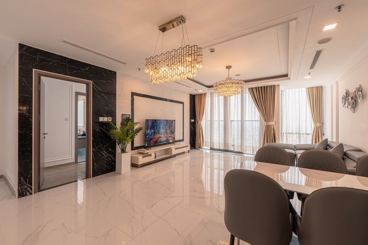 A modern living room with a flat-screen TV, a dining table, and a sofa.
