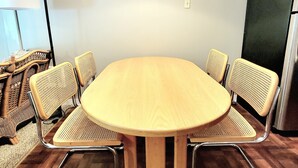 Un salón de conferencias con una mesa redonda rodeada de seis sillas de mimbre con estructura metálica.
