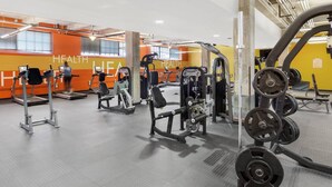 Academia com diversos equipamentos de ginástica, incluindo esteiras, aparelhos de musculação e pesos livres.