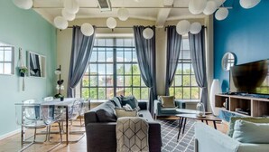 A modern living room with a sofa, TV, and dining area. - Hip & Vibrant 2 Bedroom Apartment with Parking & Wifi (Durham)