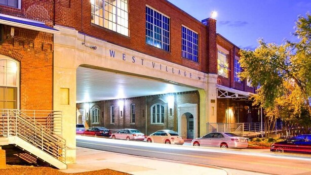 A brick building with a sign reading "WEST VILLAGE." - Hip & Vibrant 2 Bedroom Apartment with Parking & Wifi (Durham)
