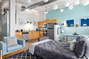 A compact living space with a kitchenette, a sofa, a bed, and a dining table. - Loft Living in the Trendy Warehouse District (Durham)