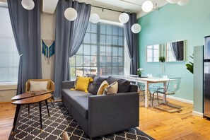 A modern living room with a grey sofa, a small round table, and a glass dining table. - 2 Bedroom Hip Apartment, Apple TV, Fast Wifi (Durham)