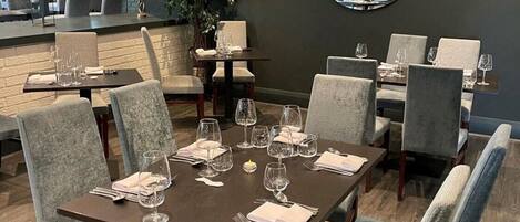 A modern dining area with a central table set for six, surrounded by upholstered chairs.