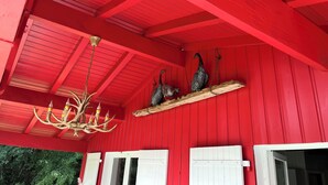 Un bâtiment rouge avec un plafond en bois, un lustre et deux oiseaux posés sur une étagère.