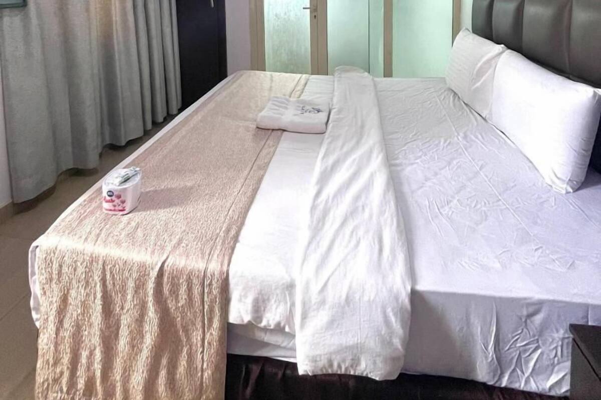 A hotel room with a bed, a TV, and a door with frosted glass panels.