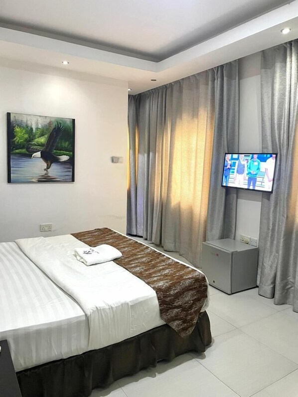 A modern hotel room with a large bed, a flat-screen TV, and a painting of an eagle.