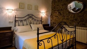 Ein Schlafzimmer mit Bett, Nachttischen, Wandleuchten, einem Spiegel und einer Steinwand.