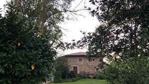 Ein Steinhaus mit Ziegeldach, umgeben von üppigem Grün und einem gepflegten Rasen.