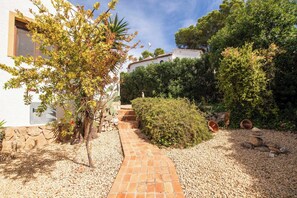 Stroll along the winding pathway to the entrance of this charming residence, surrounded by lush greenery and a serene atmosphere.