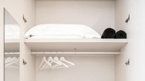 Un armario blanco con espejo, una percha y una caja fuerte pequeña.