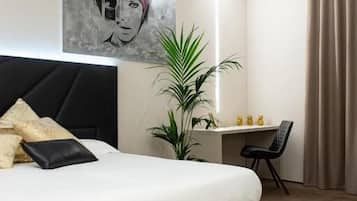 A modern bedroom with a large bed, a desk, and a potted plant.