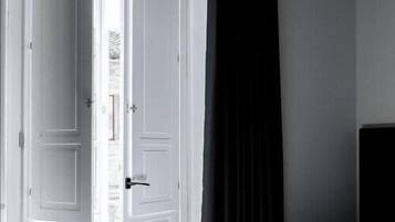 A bedroom with a bed, a white door, and a black curtain.