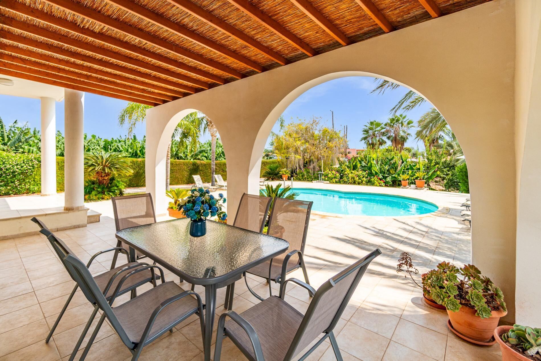 Un patio cubierto con piscina, mobiliario exterior y plantas en macetas.